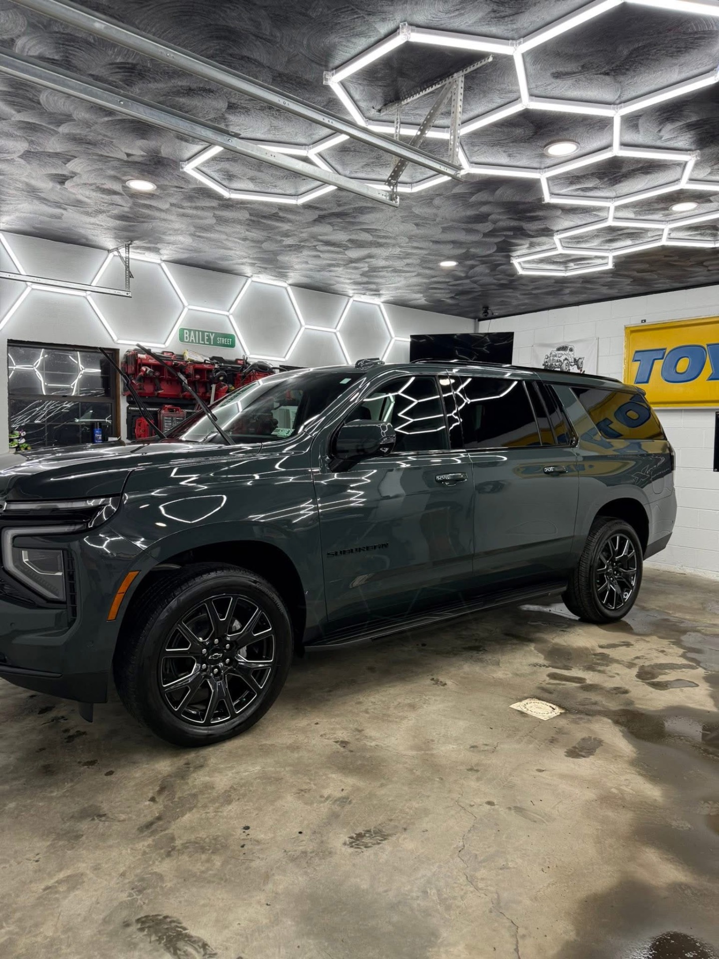 Dark grey Chevrolet Suburban gleaming under hexagon shop lights